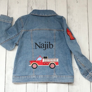 May include: A blue denim jacket with a red fire truck and fire hydrant embroidered on the back. The name "Najib" is embroidered above the fire truck.