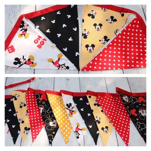 May include: A Mickey Mouse themed banner with red, yellow, black, and white triangular flags. The flags feature Mickey Mouse, polka dots, and stripes. The banner says "Oh Boy!" on one of the flags.