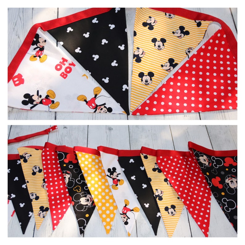 May include: A Mickey Mouse themed banner with red, yellow, black, and white triangular flags. The flags feature Mickey Mouse, polka dots, and stripes. The banner says "Oh Boy!" on one of the flags.