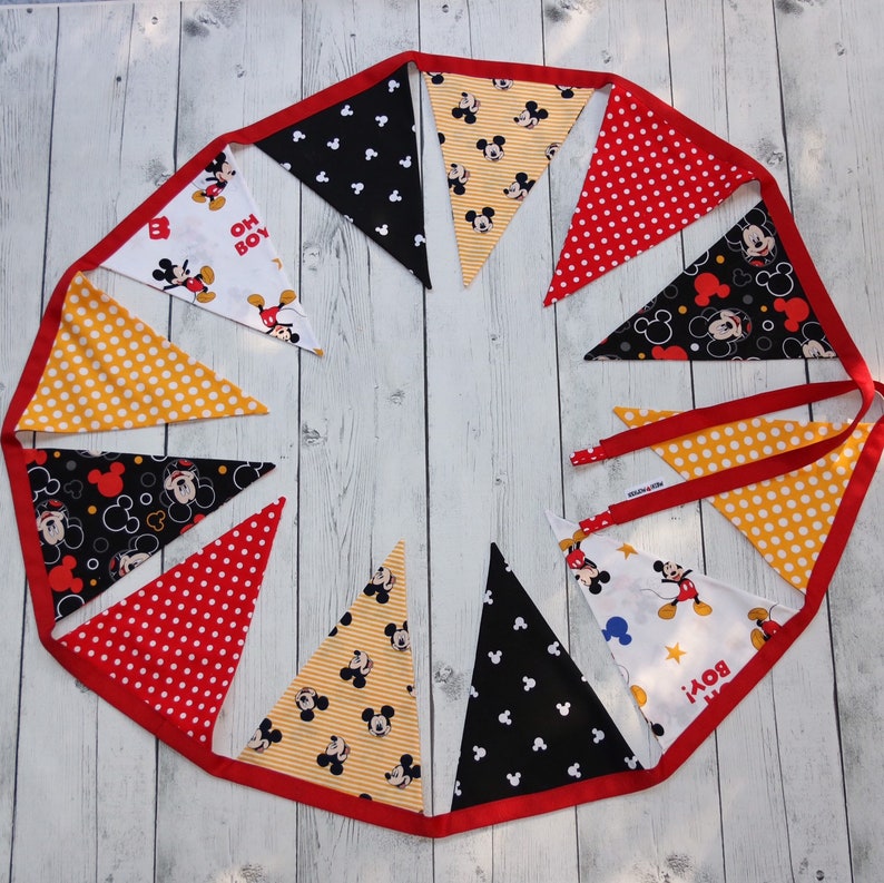 May include: A Mickey Mouse themed fabric banner with red, yellow, black, and white triangular flags. The flags feature Mickey Mouse images, polka dots, stripes, and the words "Oh Boy!"