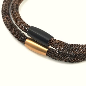 May include: A double-strand copper wire necklace with a black and gold metal clasp.