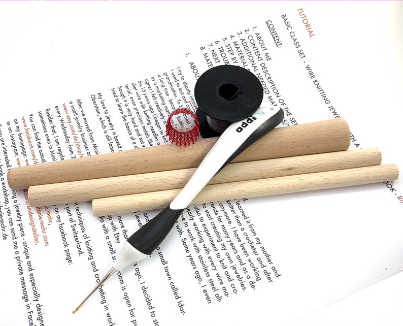 May include: A basic wire knitting jewelry kit with wooden dowels, a crochet hook, and a spool of red wire. The kit includes instructions for making jewelry.