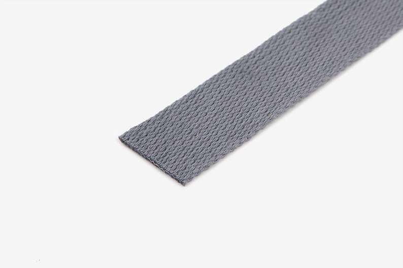 May include: A close-up of a grey woven cotton webbing strap.