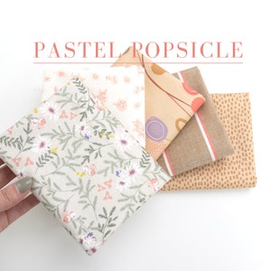 Peut inclure: Un ensemble de quatre carrés de tissu avec différents motifs pastel. Les motifs comprennent un motif floral, un motif géométrique, un motif rayé et un motif à pois.