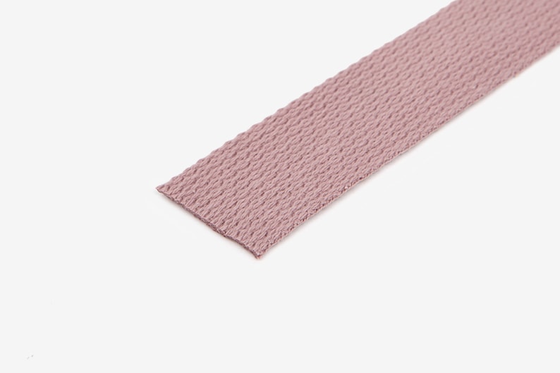May include: A close-up of a light pink woven webbing strap.