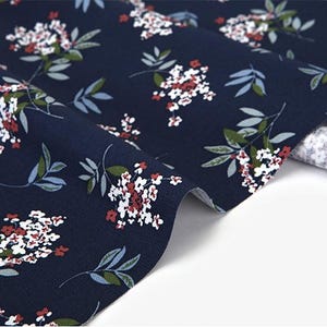 May include: Navy blue fabric with a white and red floral pattern. The fabric is folded and the pattern is visible on both sides.