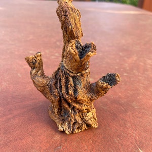 Puede incluir: Una pequeña escultura de cerámica marrón de un árbol con múltiples ramas. La escultura tiene una superficie rugosa y texturizada y parece estar hecha a mano.