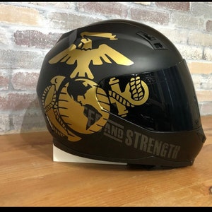 May include: Black motorcycle helmet with a gold eagle, globe, and anchor graphic. The helmet has a dark tinted visor and the text "SEMPER FIDELIS AND STRENGTH" is printed on the side.