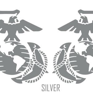 May include: A silver-coloured, stylised image of the United States Marine Corps emblem. The emblem features a globe, an eagle, and an anchor. The text "SILVER" is printed below the emblem.