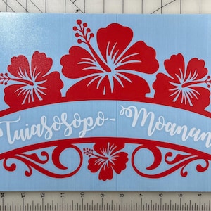 May include: Red hibiscus flower design with a white banner that reads "Tuiasosopo - Moananu". The design is on a light blue background.