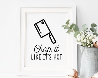 May include: White framed print with a black line drawing of a cleaver and the text "Chop it LIKE IT'S HOT". A galvanized metal pitcher holds white flowers and cotton stems.