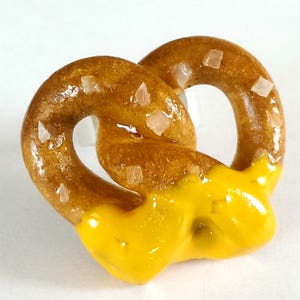 May include: A brown pretzel with salt sprinkled on top, covered in yellow icing.