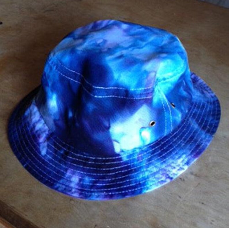 May include: A blue and purple tie-dye bucket hat with a white brim and stitching.