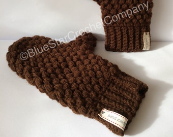 May include: A pair of brown crocheted mittens with a textured stitch. The mittens have a small tag that says "hand made".