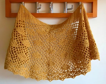 May include: A crocheted shawl in a mustard yellow color hangs on a wooden coat rack with metal hooks.