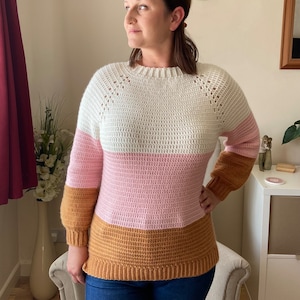 May include: A white, pink and brown striped crocheted jumper with long sleeves.