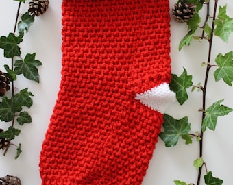 Puede incluir: Calcetín de Navidad de punto rojo y blanco con un puño de piel sintética gris.