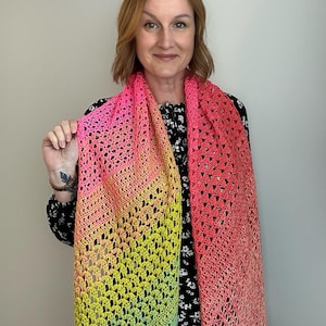 May include: A vibrant, hand-crocheted scarf in a gradient of colors, transitioning from pink to yellow and ending in a light green hue. The openwork design creates a delicate, airy texture. This accessory is perfect for adding a pop of color to any outfit.