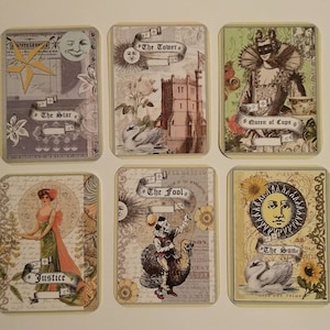 May include: A set of ten tarot cards with colorful illustrations and text. The cards feature images of a star, a tower, a queen of cups, justice, the fool, and the sun.