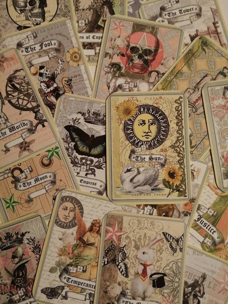 May include: A collection of tarot cards with various illustrations, including a swan, a butterfly, a sun, a moon, and a skull. The cards are decorated with floral patterns and have a vintage aesthetic.