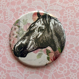 May include: A round button featuring a black and white illustration of a horse's head with floral accents. The background is white with a vintage floral pattern.
