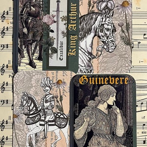 Op de afbeelding: Vier vintage kaarten met zwart-wit illustraties van een ridder, een paard, een vrouw en een zwaard. De kaarten hebben gouden letters en zijn geplaatst tegen een achtergrond van muziekpapier.
