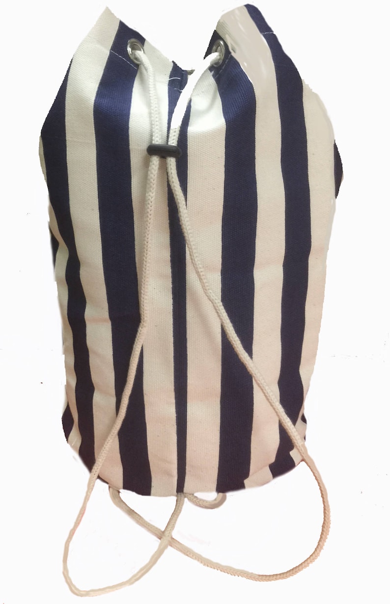 May include: A white and navy blue striped drawstring bag with a white drawstring. The bag is made of canvas and has a simple design.