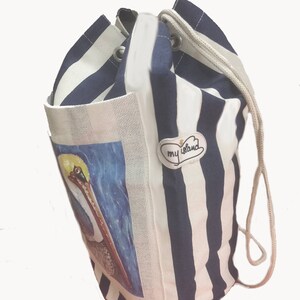 May include: A white and blue striped drawstring bag with a pelican illustration and a patch that says "my island".