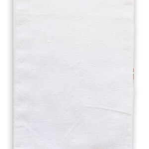 May include: A plain white cotton tea towel with a subtle texture. The towel is folded in half and has a slight crease down the middle.