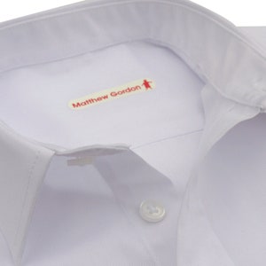 May include: White dress shirt with a white button and a red label that says "Matthew Gordon" with a small stick figure icon.