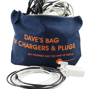 May include: A blue canvas bag with a zipper closure. The bag has the text "Dave's Bag of Chargers & Plugs" printed on the front in orange. The text "But probably not the one he needs" is printed below in smaller orange letters. A white electrical plug and a tangle of black and white cords are visible outside the bag.