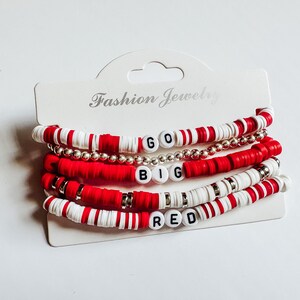 May include: Set of five red and white beaded bracelets with the words "GO BIG RED" spelled out in black beads.