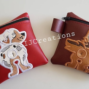 May include: Two small, square pouches with zip closures and attached loops. One is red with a dog embroidery, the other is brown with a dog embroidery. The pouches have black zips and are likely for small items.