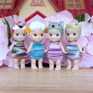 Puede incluir: Cuatro peque&ntilde;as mu&ntilde;ecas que llevan trajes de ba&ntilde;o de ganchillo y sombreros de animales. Las mu&ntilde;ecas est&aacute;n de pie sobre una superficie de madera. Las mu&ntilde;ecas llevan una variedad de colores, incluyendo arco&iacute;ris, azul, morado y verde.