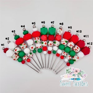 Puede incluir: Doce juegos de cuentas de silicona y palitos de metal con temática navideña. Cada juego tiene una combinación diferente de cuentas rojas, blancas y verdes con un patrón de Papá Noel. Los juegos están numerados del 1 al 12.