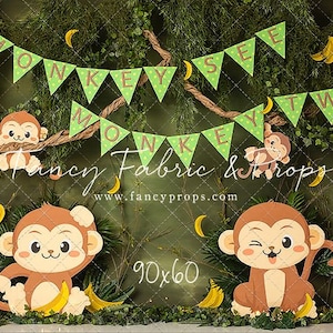 May include: A green jungle backdrop with a banner that reads "Monkey See Monkey Do Two". There are several monkeys with yellow bananas hanging from the branches.