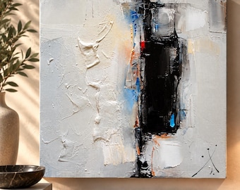 May include: A square abstract painting featuring a thick, textured impasto application of white, gray, and black paint. A prominent vertical black shape dominates the center, accented by small touches of blue, orange, and red, with a signature in the corner.