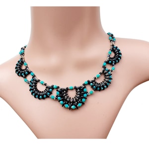 Könnte beinhalten: Eine türkisfarbene und schwarze Perlenkette mit geometrischem Design. Die Kette besteht aus mehreren kreisförmigen Mustern aus schwarzen und türkisfarbenen Perlen.