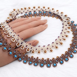 Può includere: Due collane di perline con intricati motivi intrecciati. Una collana è realizzata con perline bianche e accenti color bronzo, mentre l'altra presenta perline marrone metallizzato con perline circolari turchesi e piccoli cristalli trasparenti.