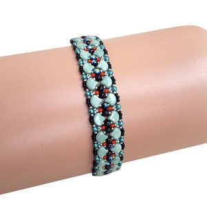 May include: A turquoise, black, and orange beaded bracelet with a geometric pattern. The bracelet is made with small, round beads and is shown on a mannequin arm.