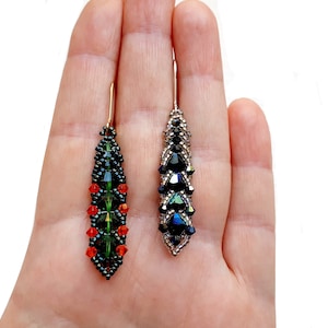 May include: A pair of dangle earrings featuring black, green, and red beads. The earrings are crafted in a teardrop shape and hang from a gold hook.