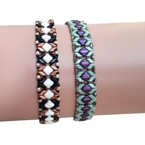 May include: Two beaded bracelets featuring a woven pattern of diamond-shaped beads. The left bracelet combines white, black, and metallic copper beads. The right bracelet features a combination of light sage green and deep purple diamond-shaped beads.