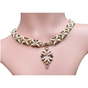 May include: A white and brown beaded necklace with a pendant featuring a geometric design. The necklace is made with small, round beads and has a delicate, feminine look.