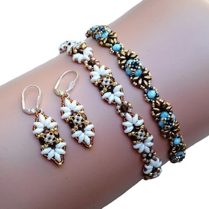 Può includere: Un set di gioielli in perle con un braccialetto bianco e oro e orecchini abbinati. Il braccialetto ha un accento di perle blu e oro.