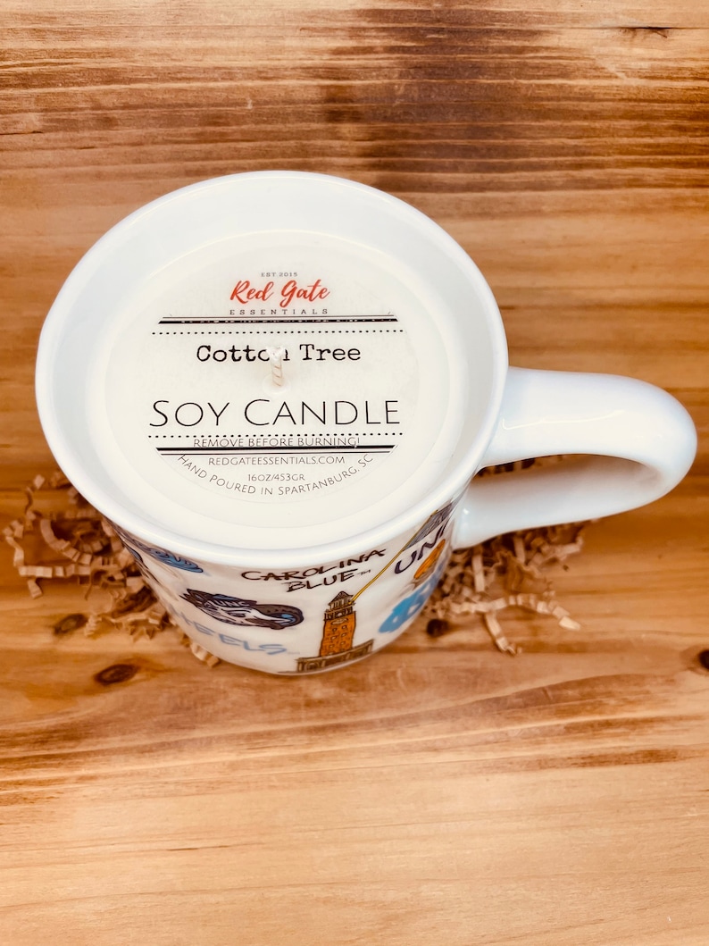 Peut inclure: Une tasse en c&eacute;ramique blanche remplie d'une bougie de soja. La bougie est &eacute;tiquet&eacute;e "Cotton Tree" et "Soy Candle". La tasse a une anse et est d&eacute;cor&eacute;e d'images de Carolina Blue. La bougie p&egrave;se 453 grammes.