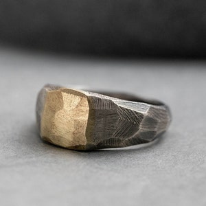 Brutalist signet ring for men and women in sterling silver with real 14K gold on top. The ring is faceted by hand and it is darkened for a more rough style.
