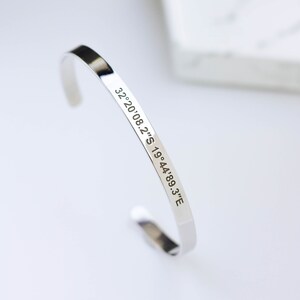 Puede incluir: Un brazalete de plata con las coordenadas "32.20'08.2"S 19.44'89.3"E" grabadas.