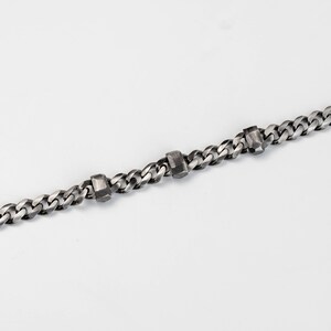 A Cuban link chain bracelet with faceted links for men in black oxidized silver