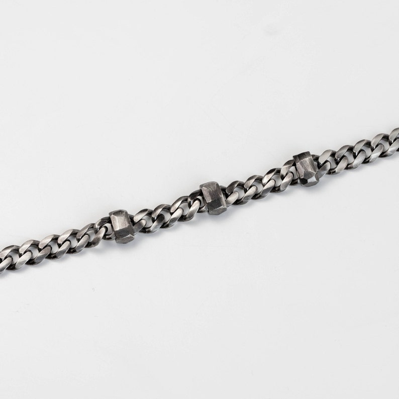 A Cuban link chain bracelet with faceted links for men in black oxidized silver