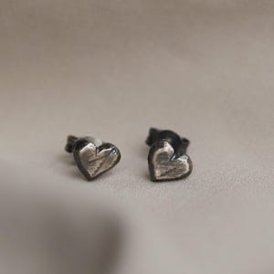 May include: A pair of silver heart-shaped stud earrings with a textured finish.